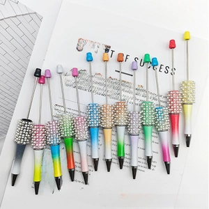 Detail of colorful gradient DIY beadable pens with white pearl decoration on white paper