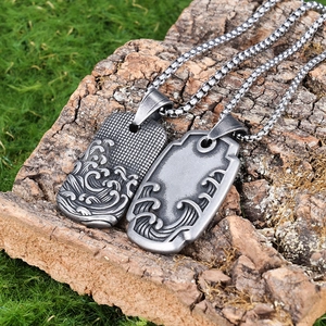 Gros plan de pendentifs vintage en acier inoxydable avec totem de vague sur écorce