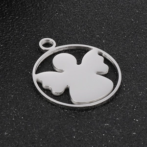 Detailed view of silver stainless steel angel pendant on a black textured background