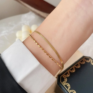 Dual layer 18k gold plated herringbone and bead chain bracelet worn with stylish attire