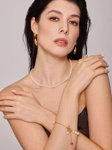 Détail d'un bracelet en perles d'eau douce et boucles d'oreilles avec pierres rouges