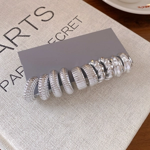 Detailed close-up of a silver earring set with textured and smooth hoop designs