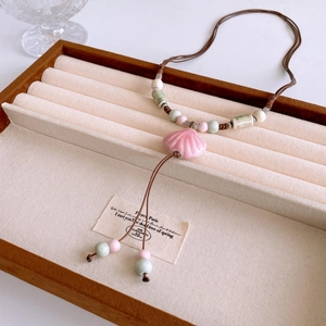 Macro detail of bohemian ceramic necklace with pink shell pendant and braided cord