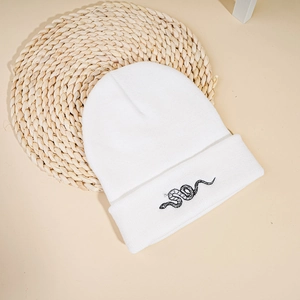 Close-up of snake embroidery on premium white knit beanie showing fine stitch texture