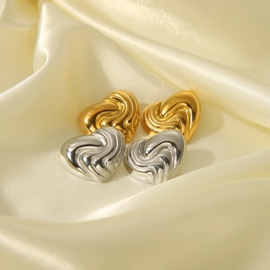 Dettaglio di orecchini a cuore oro e argento con motivi a trama a vortice particolari