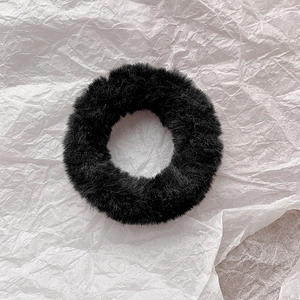 Close-up of soft black plush scrunchie with faux rabbit fur texture on white background