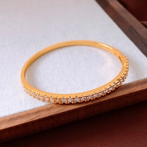 Macro shot of gold plated bangle featuring a half circle of pave set shimmering cubic zirconia