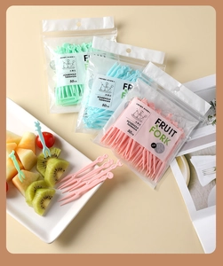 Macro view of disposable two-prong plastic fruit forks in pink, green, and blue colors