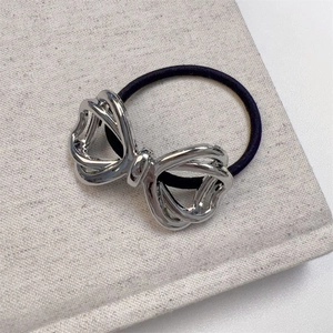 Silver hollow bow metal hair tie with black elastic band shown at a 45-degree angle