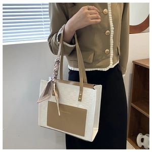 Detail of two-tone tote bag featuring woven texture and decorative silk scarf handle