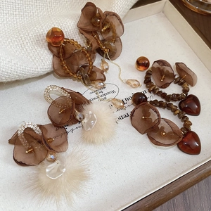 Detail of vintage earrings set featuring amber beads, organza petals, and soft plush balls