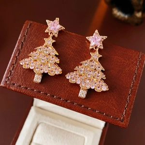Macro view of gold Christmas tree earrings with pink and white cubic zirconia on leather box