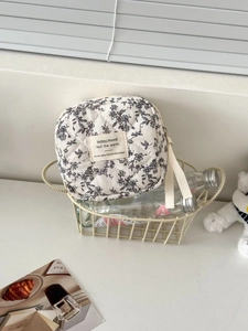 Detailed close-up of quilted floral sanitary pouch in a minimalist lifestyle setting