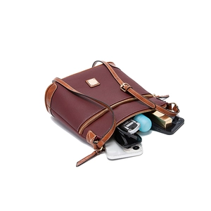 Close-up of deep wine red pebble grain crossbody bag with brown trim and interior storage