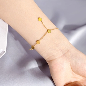 Elegant gold chain bracelet with five polished circular charms on a purple satin background