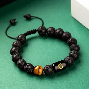 Tiger eye and lava stone beaded bracelet with gold letter C on dark green background