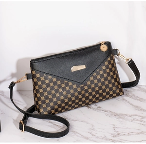 Detail of crossbody bag featuring circle pattern, metal plaque and coin zipper puller