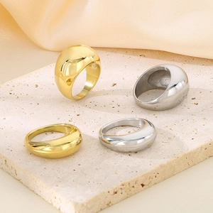 Polished gold and silver stainless steel rings on stone surface with soft fabric