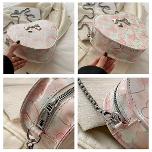 Detail view of pink tie-dye heart-shaped bag with metal bow and silver chain strap