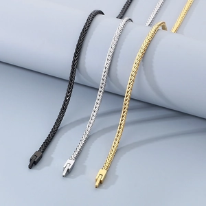 Macro detail of braided wheat chain links in black, silver and gold stainless steel