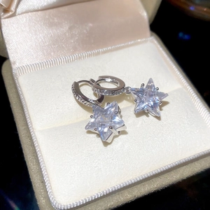 Macro shot of silver star drop earrings with clear cubic zirconia in a beige velvet box
