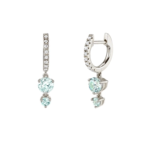 Macro view of silver dangling earrings with white diamonds and light blue gemstones