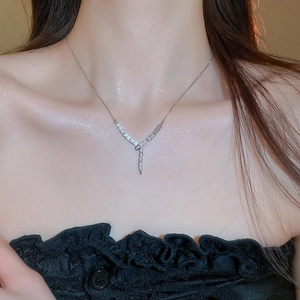 Detail of a sparkling silver Y-shaped zircon necklace on model with shimmering skin