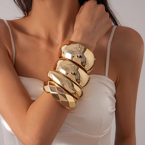 Close-up of four chunky gold-plated alloy bangles set worn by a fashion model