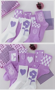 Flat lay of purple and white cotton socks with cute patterns like hearts and smiling faces
