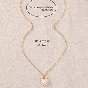 Elegant gold heart pendant necklace with pearl white center on soft beige linen fabric