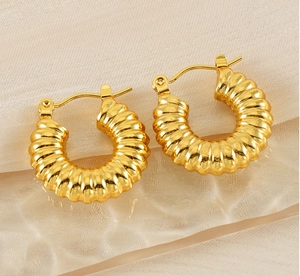 Macro shot of 18K gold plated croissant dome earrings with spiraled texture on silk