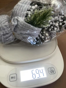 Detailed view of a 20cm mini Christmas tree with silver ribbon being weighed on a scale