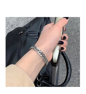 Close-up of a silver titanium steel Cuban link bracelet worn on a model's wrist