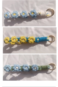 Close-up of handmade woven daisy charms with gold metal rings in various colors