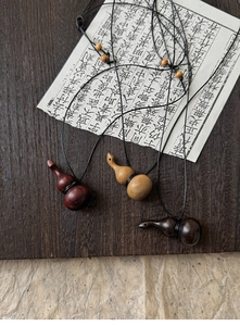 Gros plan de pendentifs gourde en bois en trois finitions naturelles sur fond vintage