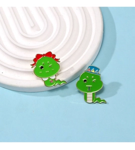 Detailed close-up of cartoon enamel snake brooches with green finish and festive designs