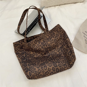 Detail view of large leopard print tote bag next to a laptop showing spacious capacity
