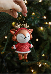 Detail of glittery red and gold reindeer ornament hanging on a festive Christmas tree