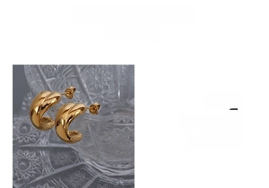 Macro detail of gold 18K plated crossover twist hoop earrings on a decorative glass rim