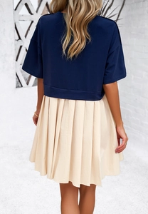 Vista posteriore di un abito elegante con top blu scuro e gonna a pieghe beige a maniche corte