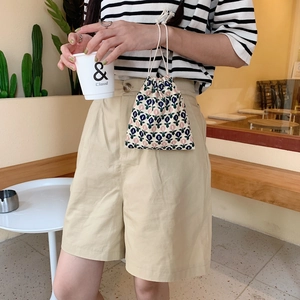 Close-up of small floral drawstring bag with retro pattern held by model in a cafe