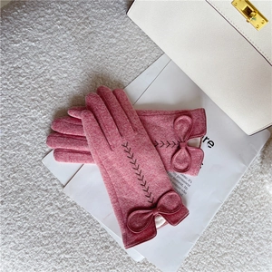 Detailansicht rosa Wollhandschuhe mit eleganter Schleife und dekorativem Weizenstich-Muster.
