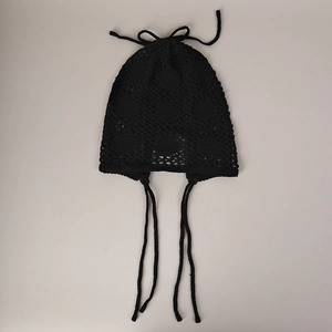Détail d'un bonnet au crochet noir avec motifs ajourés et rubans de fixation