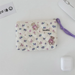 Macro view of floral quilted cotton bag with teddy bear pattern and purple cord zipper