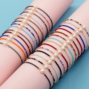 Bohemian colorful seed bead bracelets with pearl and gold accents on model wrist