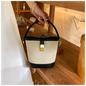 Detail of a contrast canvas handbag with black leather trim and golden metal lock