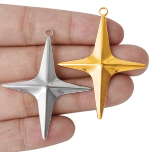 Golden and silver 304 stainless steel four-pointed star pendants held in a hand