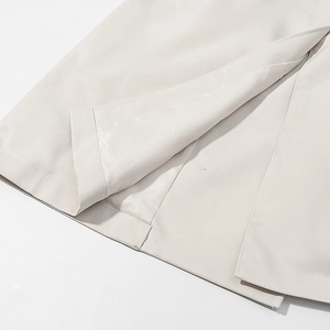 Detail of double-stitched hem and slit on beige trench coat with smooth lining