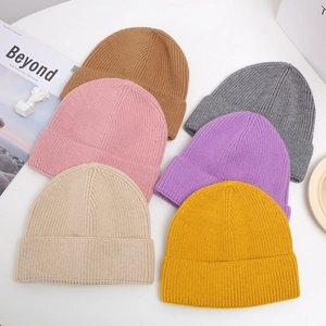 Flat lay of ribbed knit beanies in various colors like yellow, pink, and grey for winter