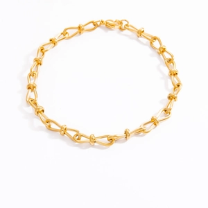 Detailed view of handmade woven leaf chain bracelet in golden finish on white background